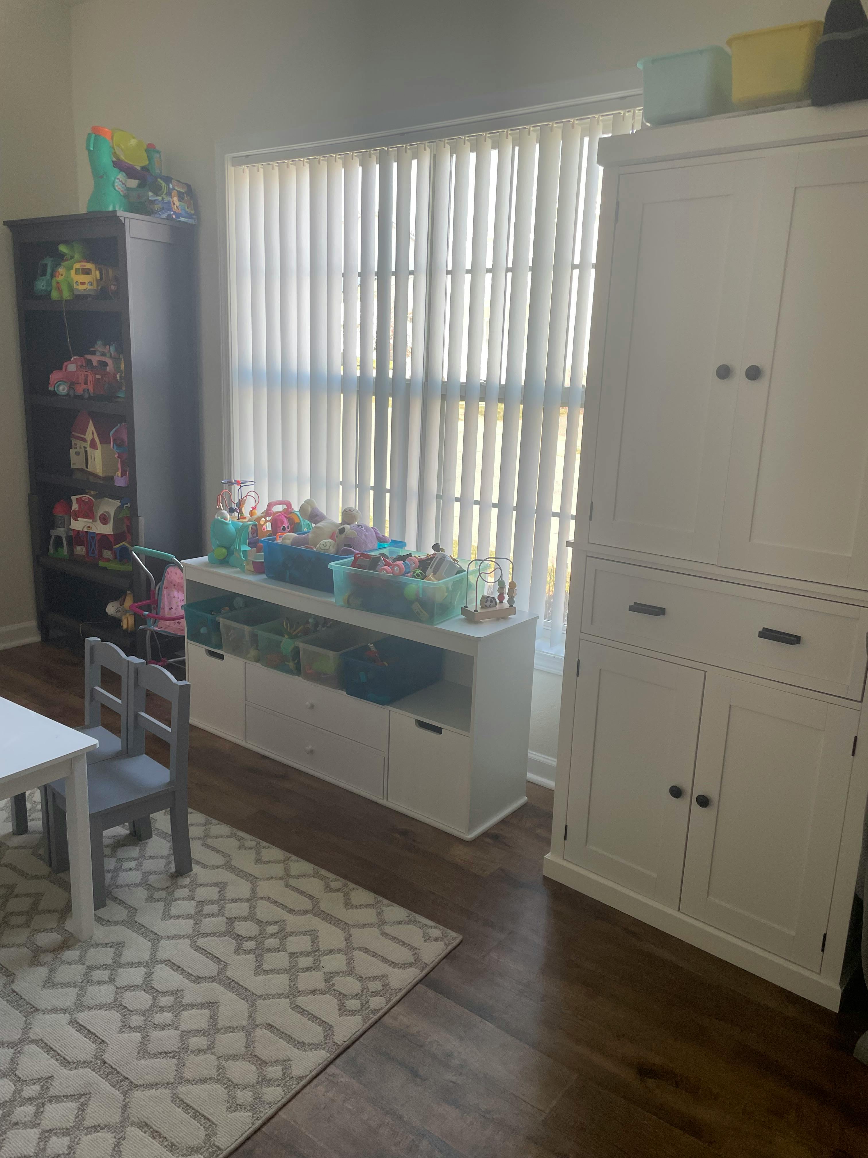 Playroom with toy storage, white table and chairs, and a patterned rug