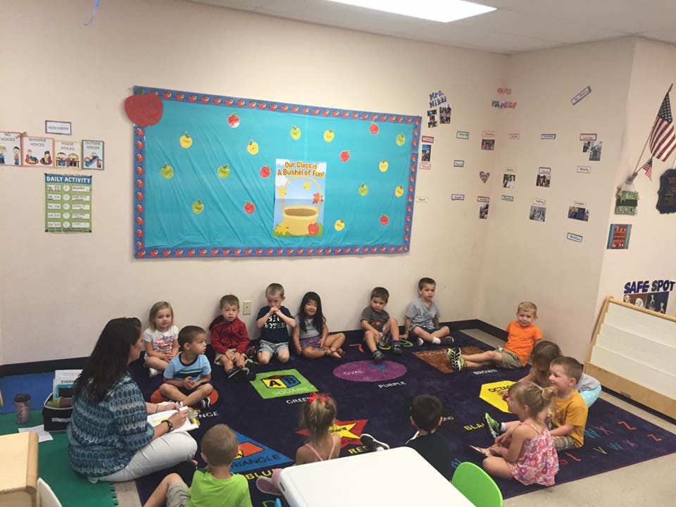 Adult reading to children sitting on a rug in a classroom