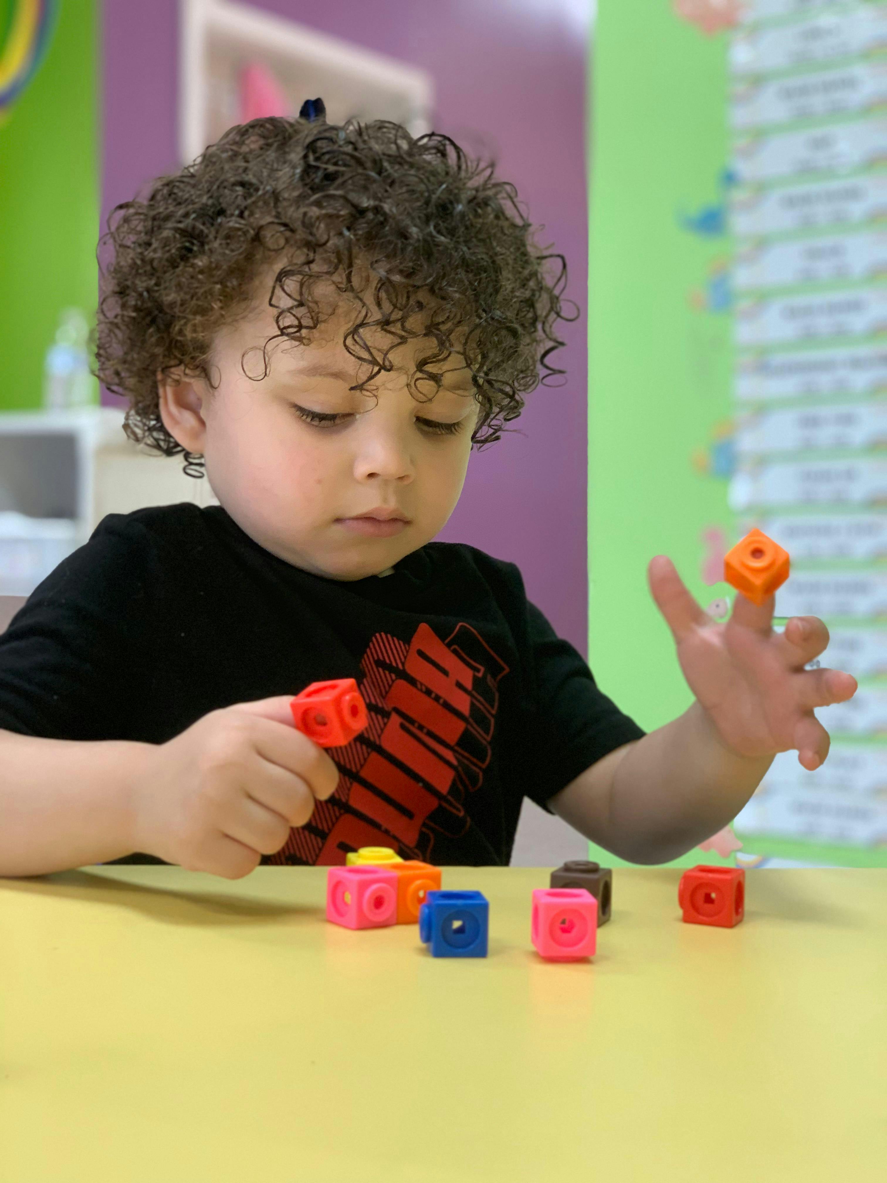 Child playing with colorful interlocking cubes at a table