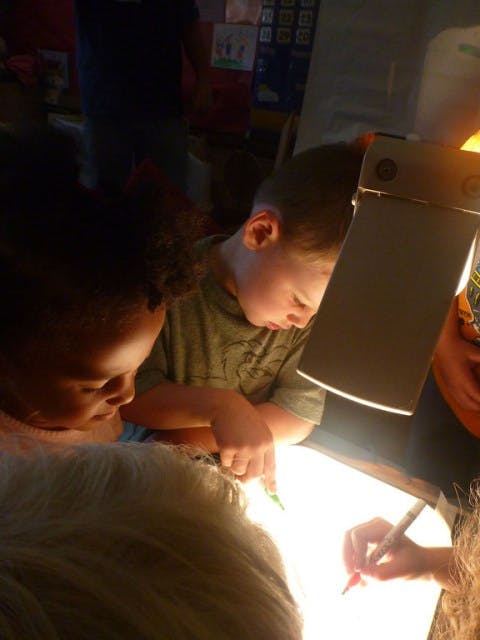Children drawing on a light table