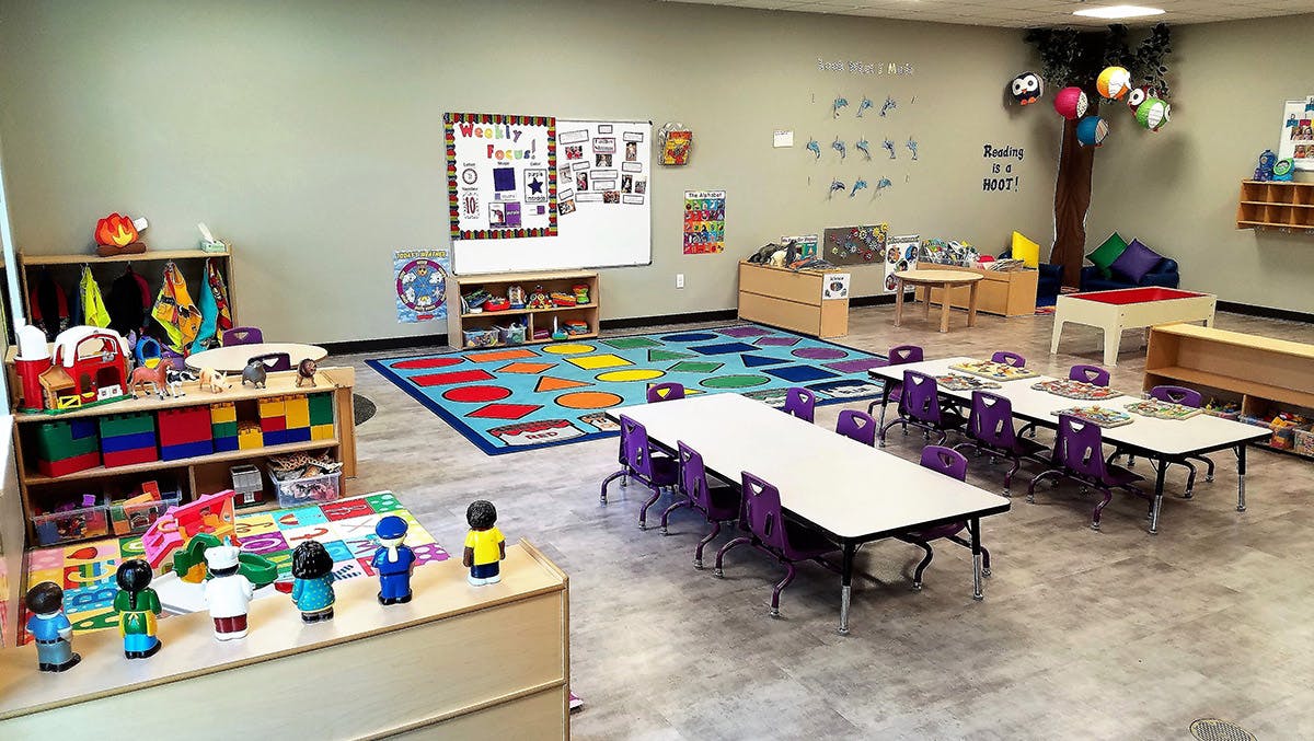 Classroom with tables, chairs, and colorful rug