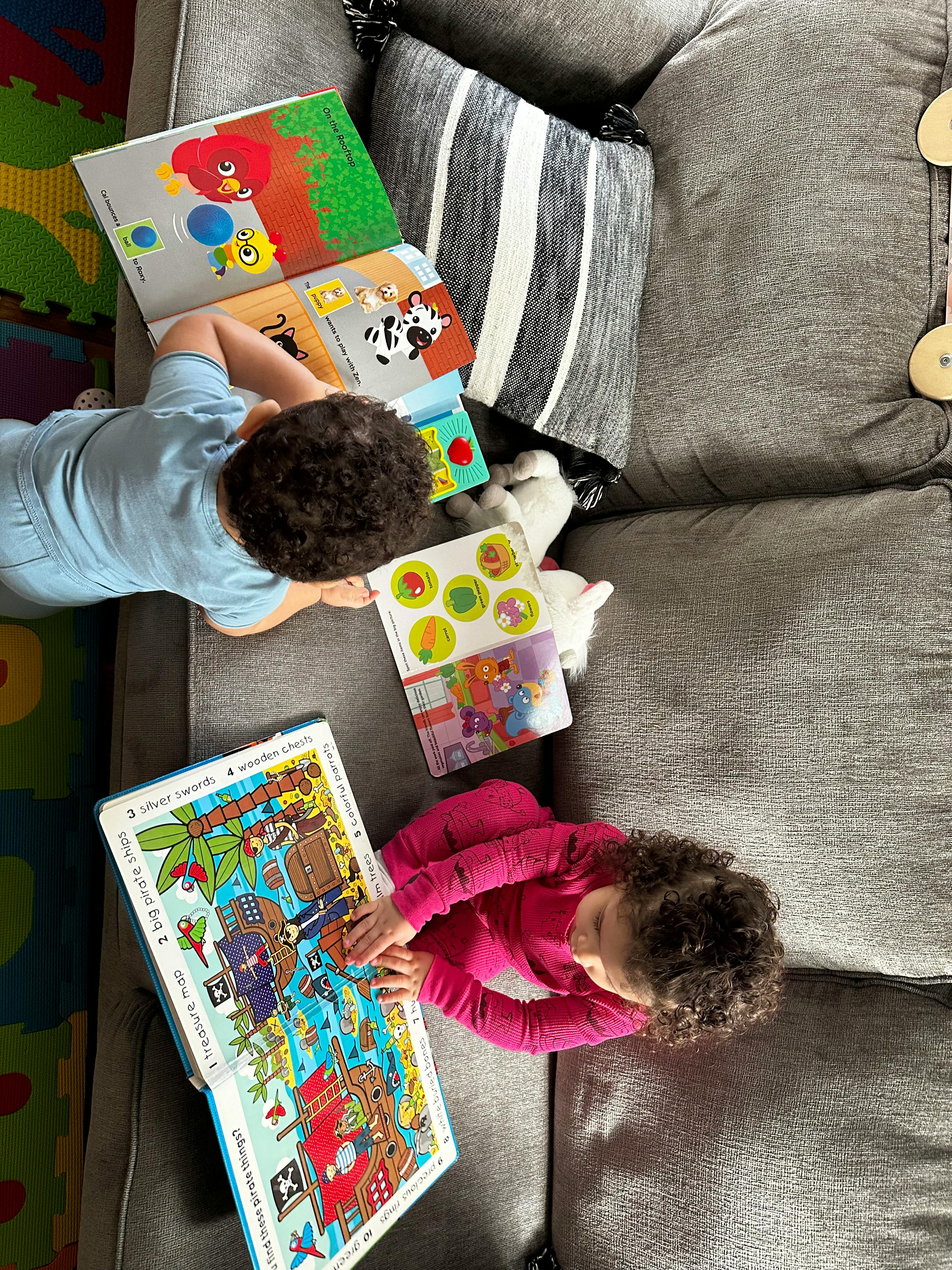 Two children lying on a couch looking at books