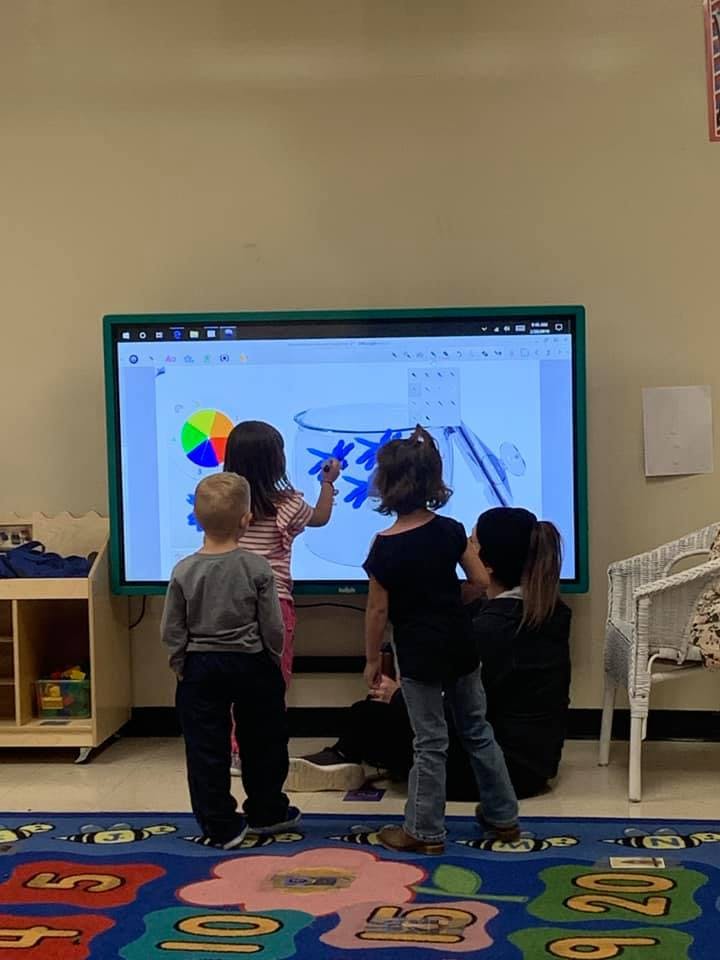 Children interacting with a large digital screen in a classroom