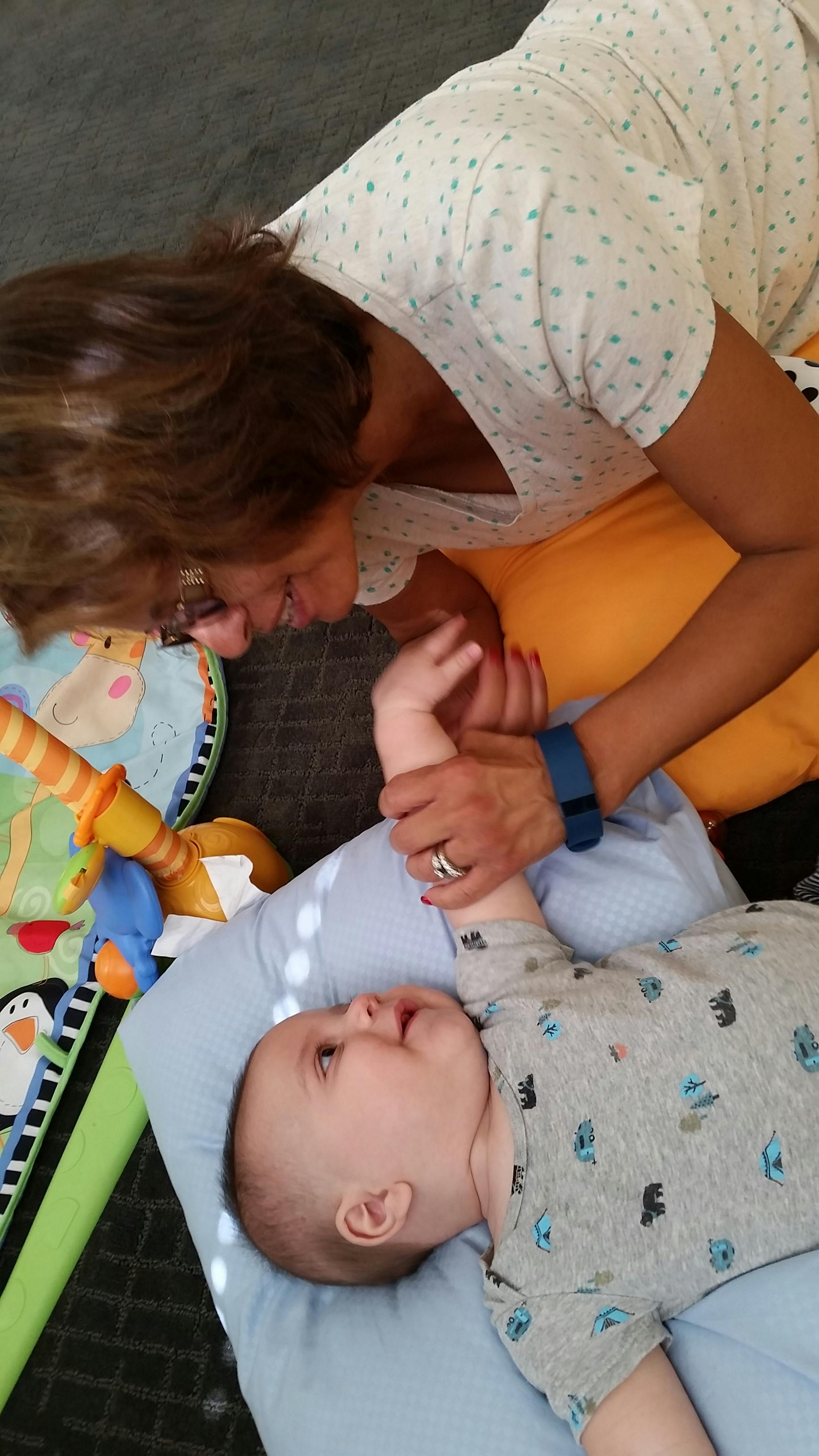 Person interacting with a child lying on a pillow