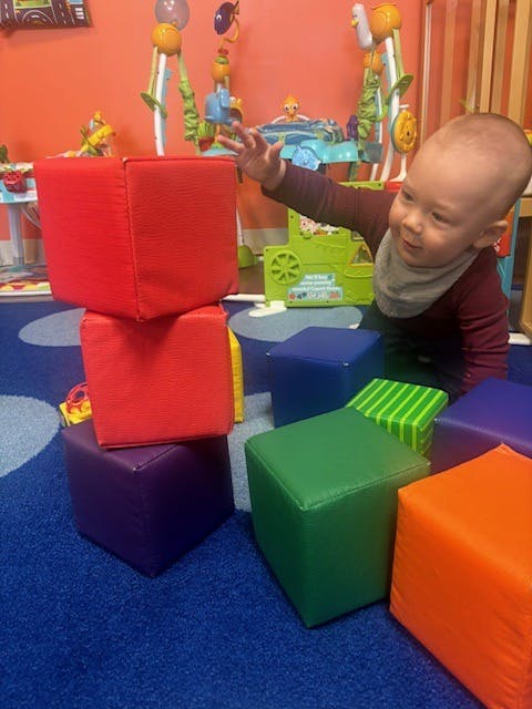 A child playing with foam blocks on a rug