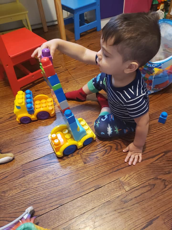 Child playing with colorful building blocks on a wooden floor