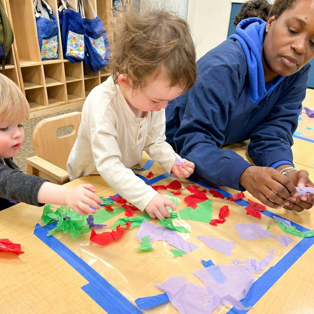 Two children and an adult doing an art project with colorful paper