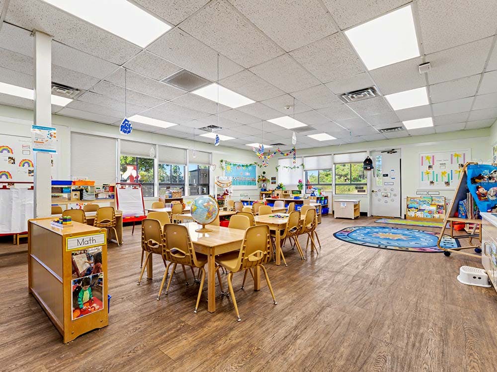 Empty classroom with small tables and chairs, and a globe on one table