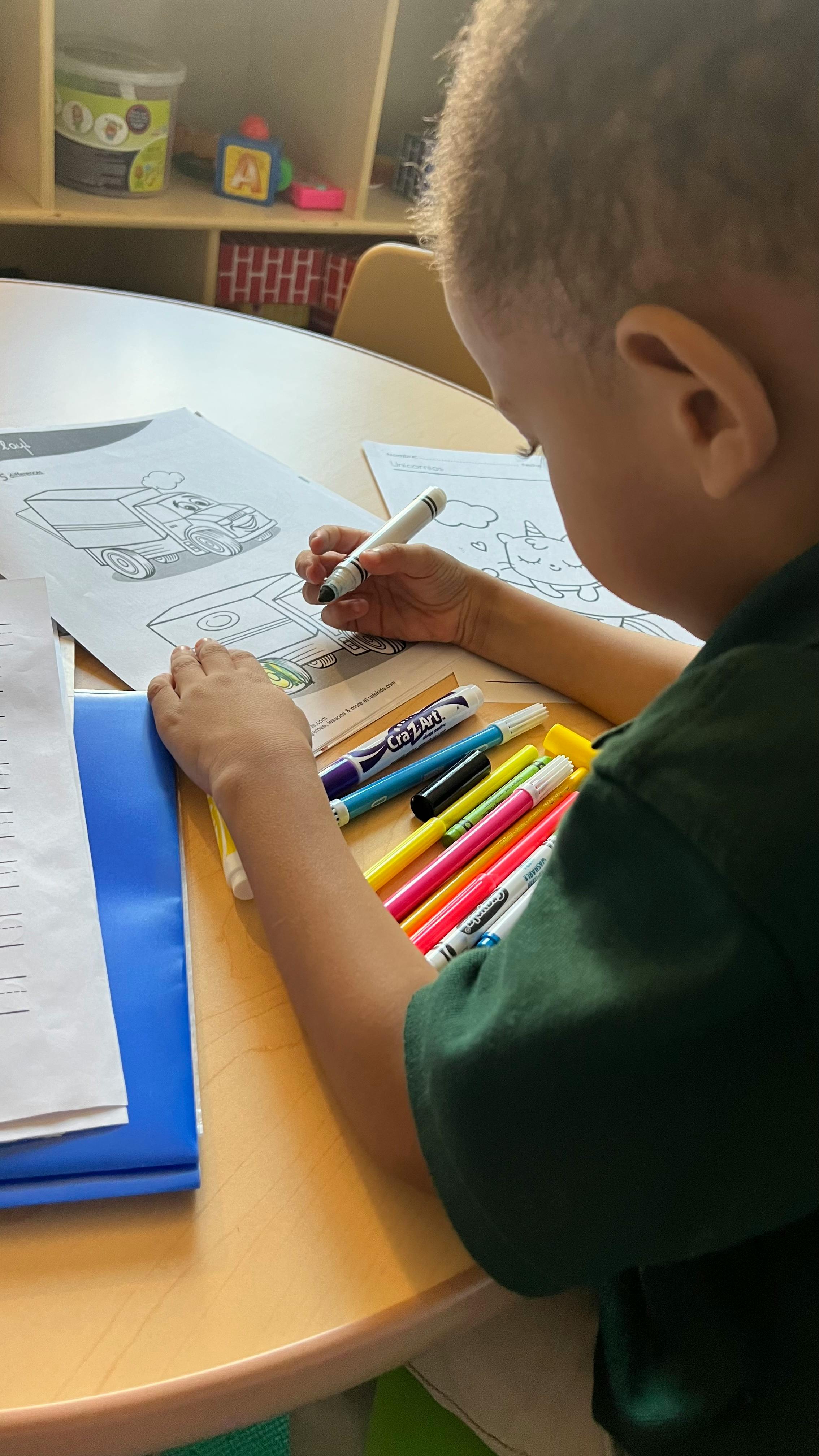 Child coloring a picture of a truck at a table