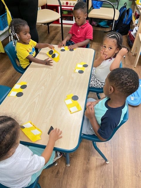 Children sitting at a table with yellow paper cutouts