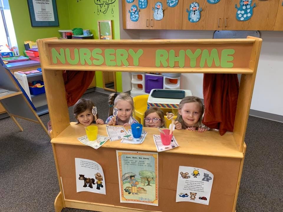 Children playing in a toy stand with "NURSERY RHYME" written on top