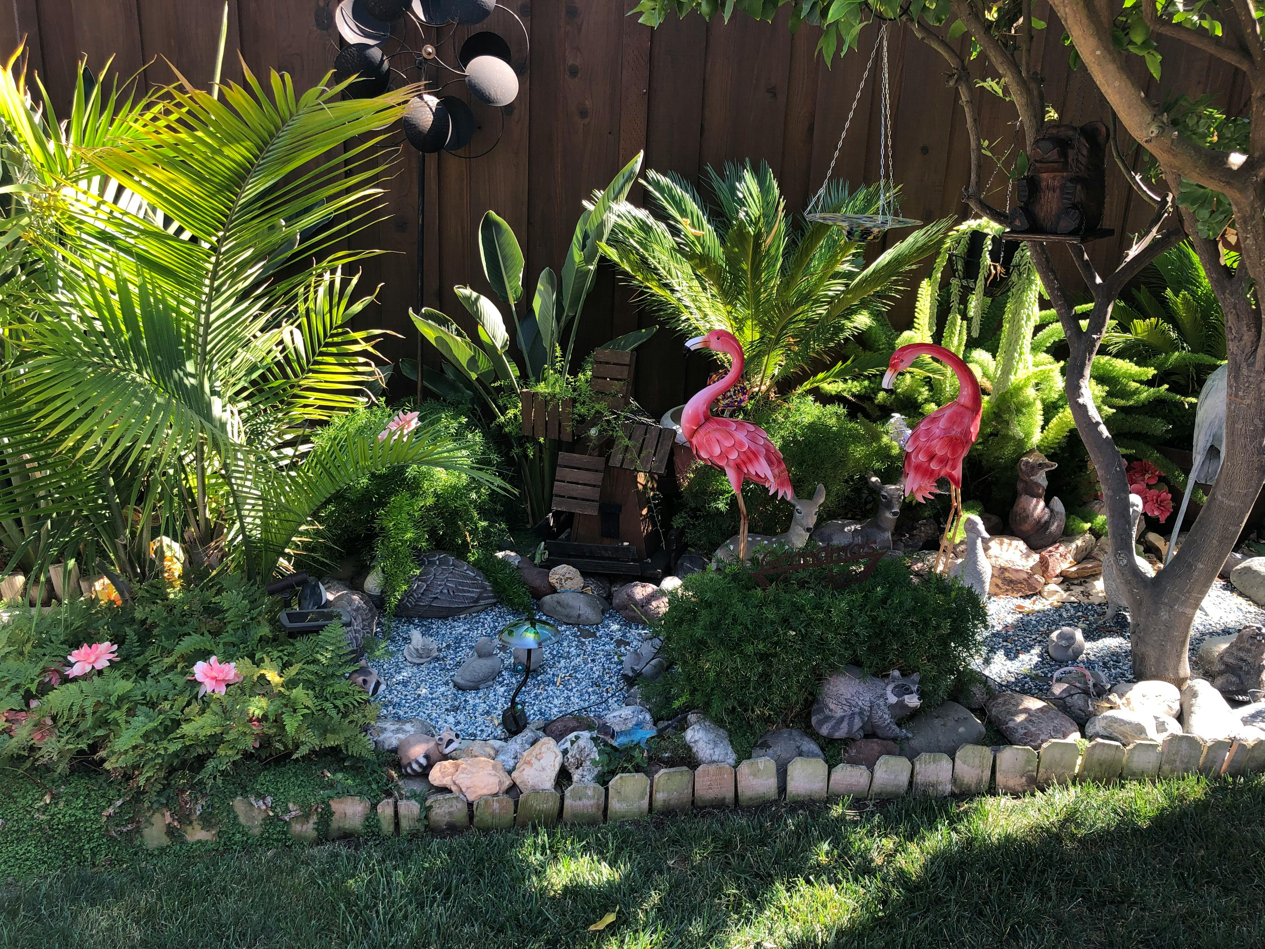 Garden with two pink flamingo statues and various plants