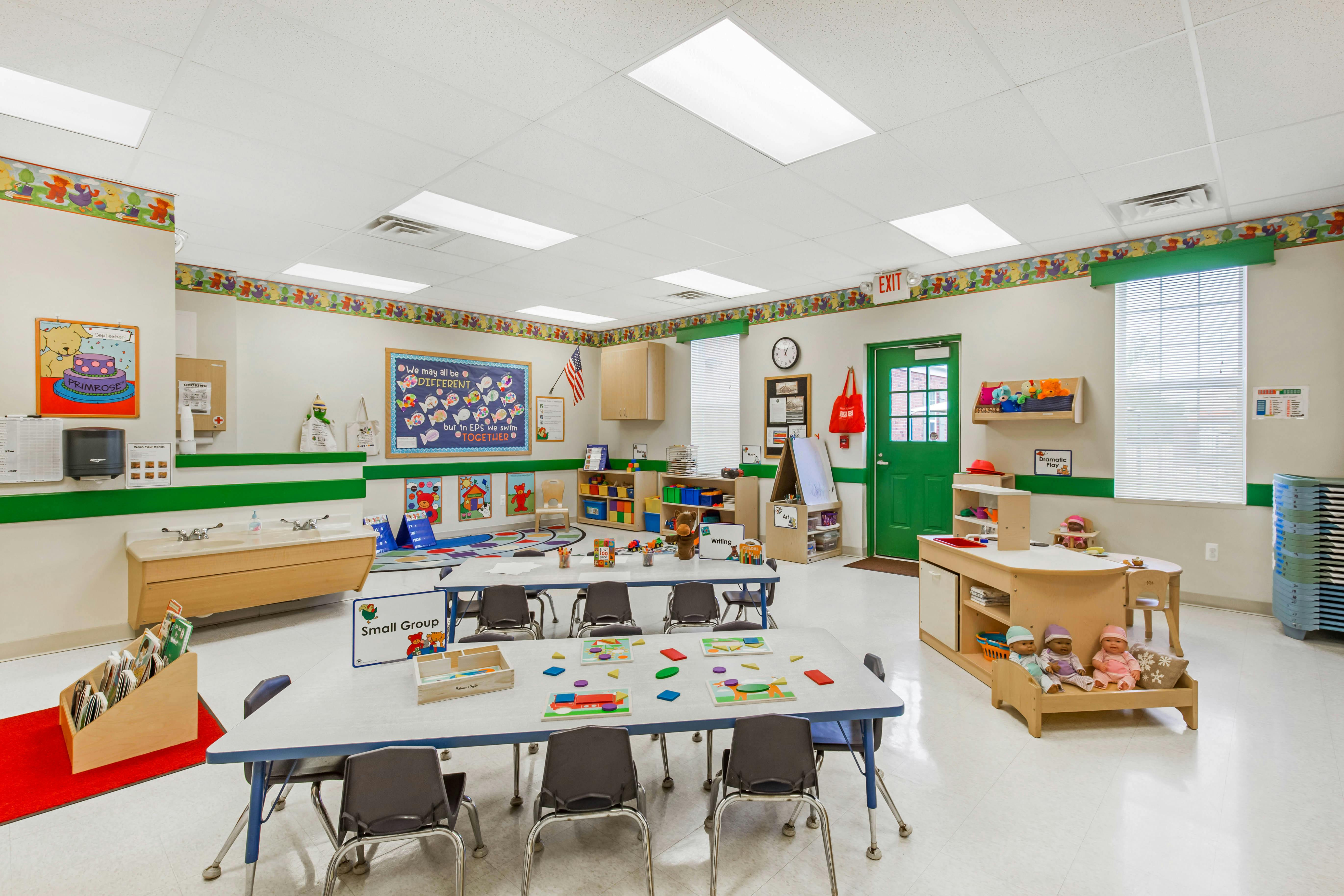 An empty early elementary school classroom with small tables and chairs