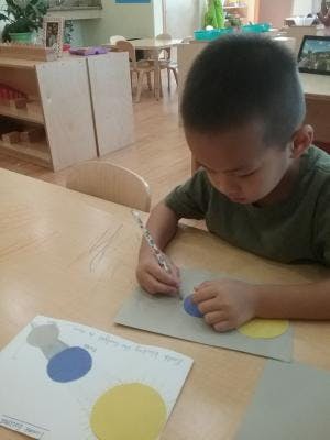 Child drawing on paper with a stencil