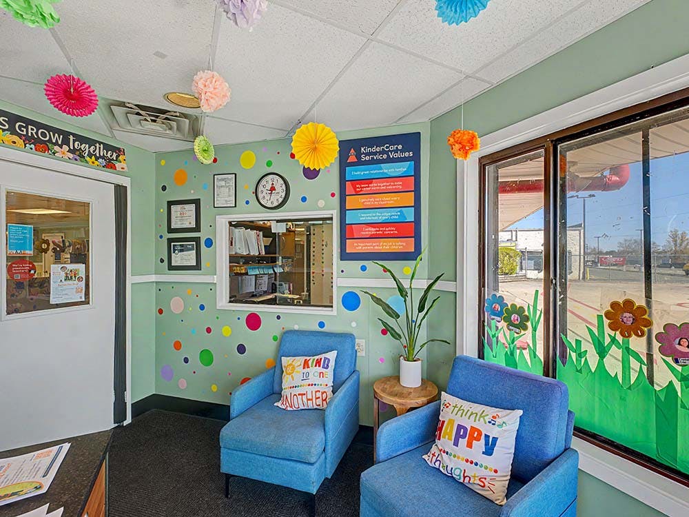 Children's waiting area with two blue armchairs, a plant, and colorful decorations