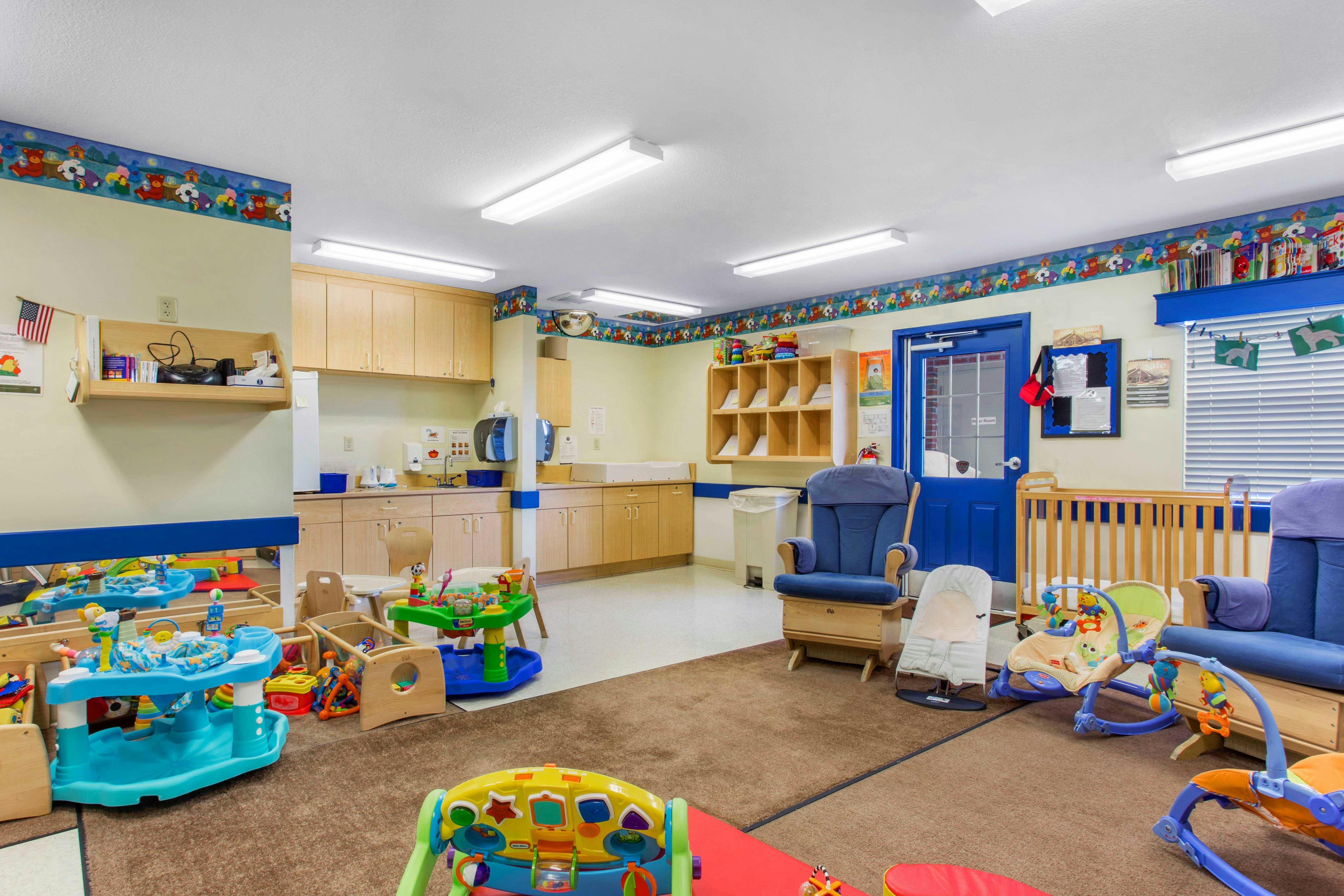 Daycare room with cribs, rocking chairs, and toys