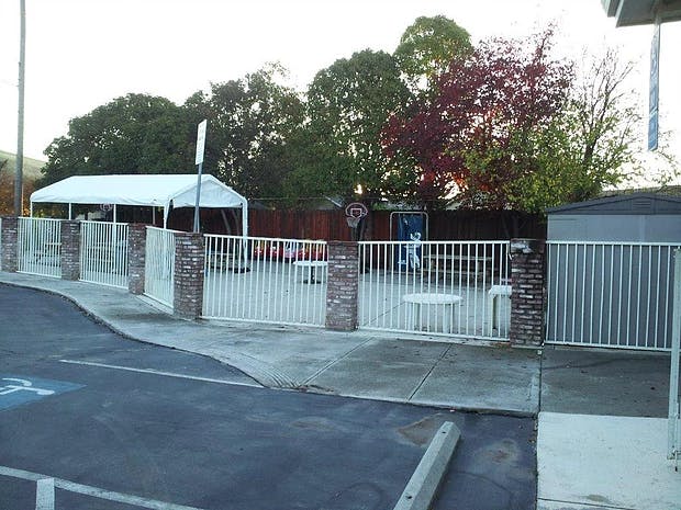 White tent behind a white fence with brick pillars