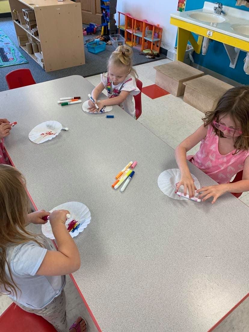 Children drawing on paper plates in a classroom