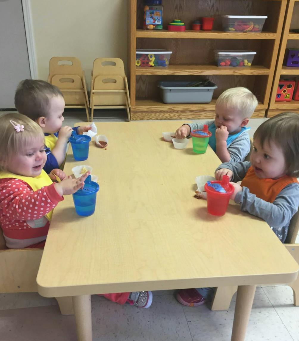 Four children sitting at a table with cups
