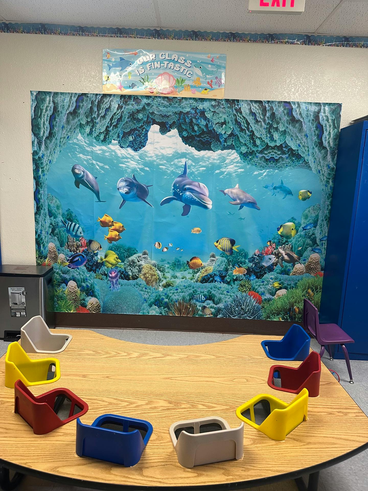 Classroom table with colorful floor seats in front of an ocean mural