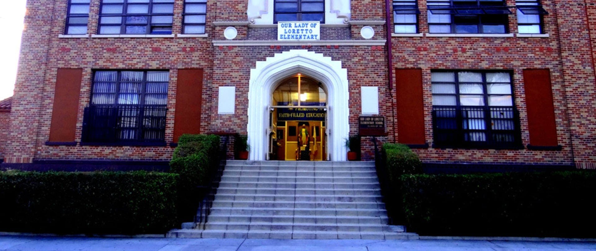 Our Lady of Loretto Elementary school building entrance with stairs and bushes