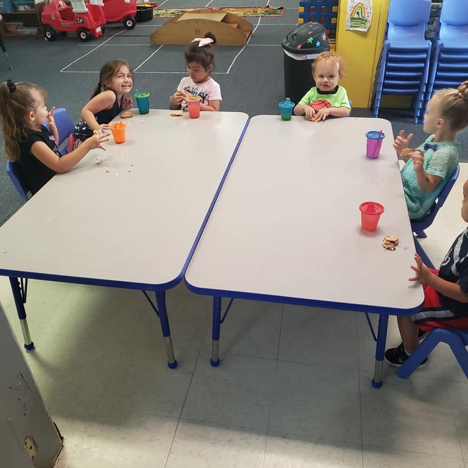 Children sitting at tables with cups