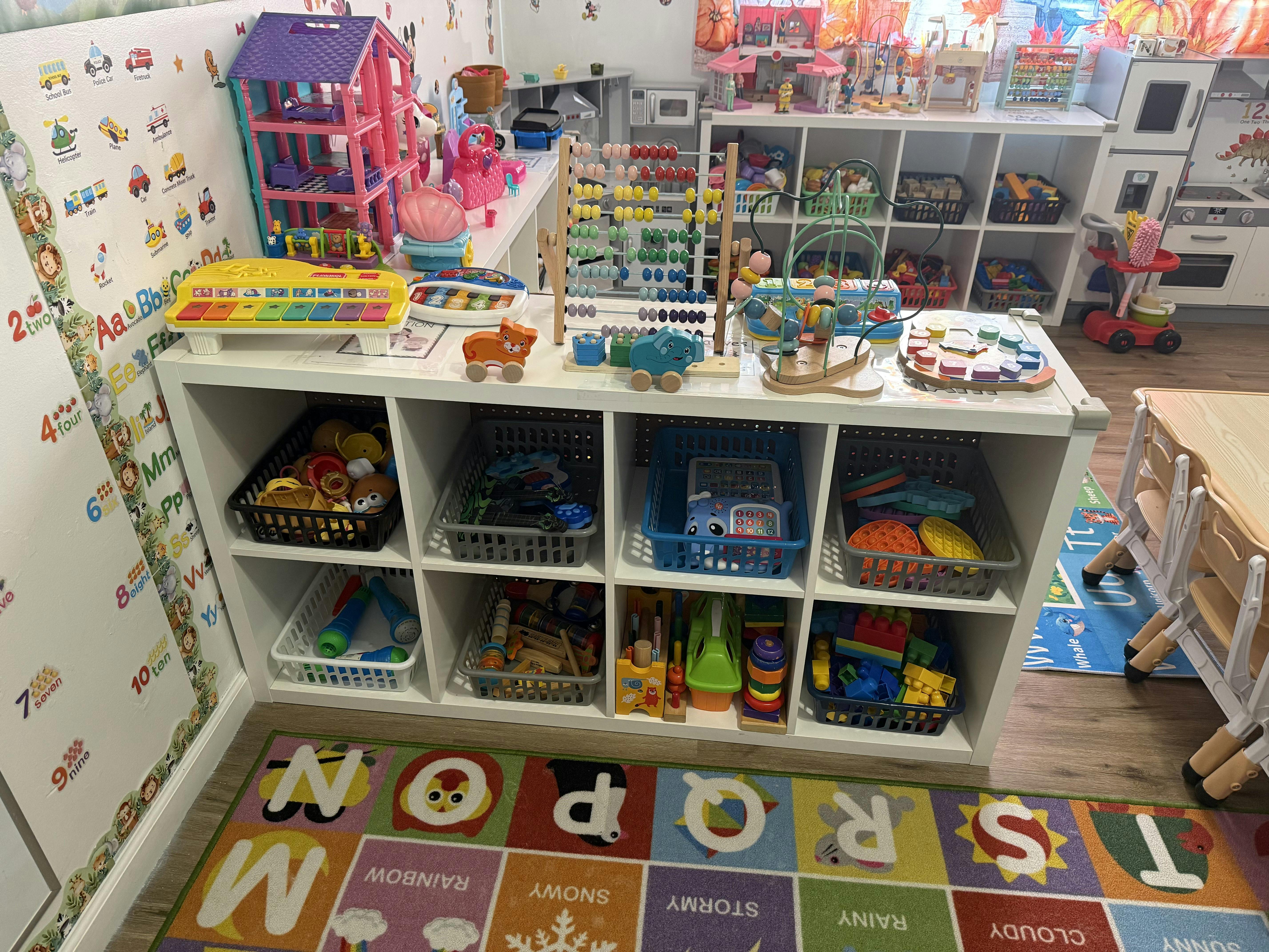 white shelves filled with various colorful toys, with an alphabet rug on the floor