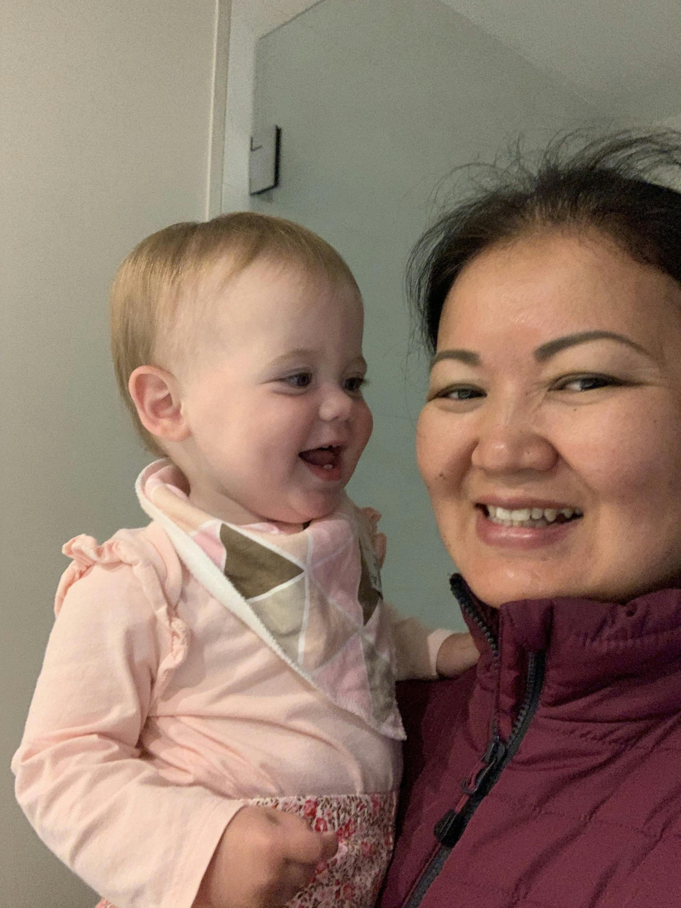 Smiling person holding a child wearing a bib