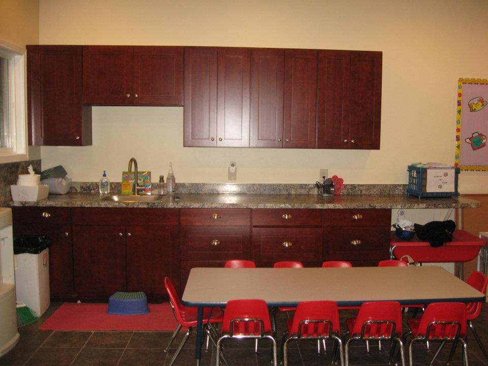 Kitchenette with dark wood cabinets, sink, and a table with red chairs