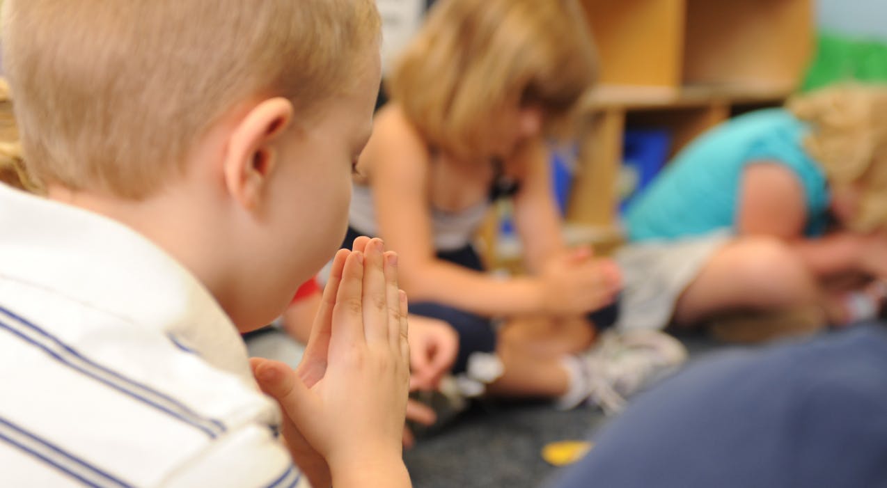 Child with hands together in a classroom