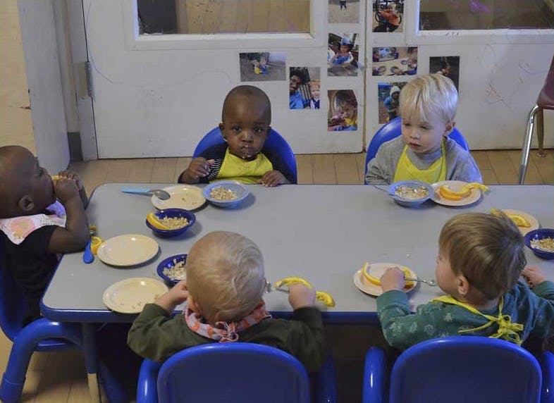 Four children sitting at a table with plates and bowls