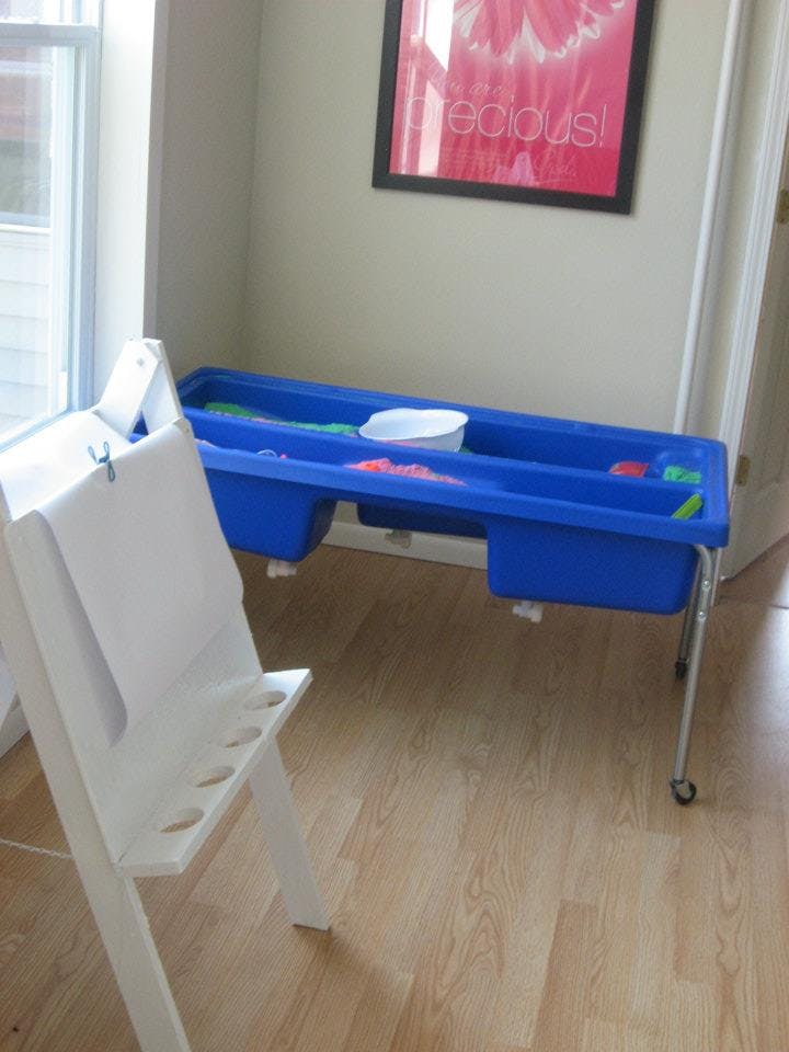 White easel and blue sensory table with toys
