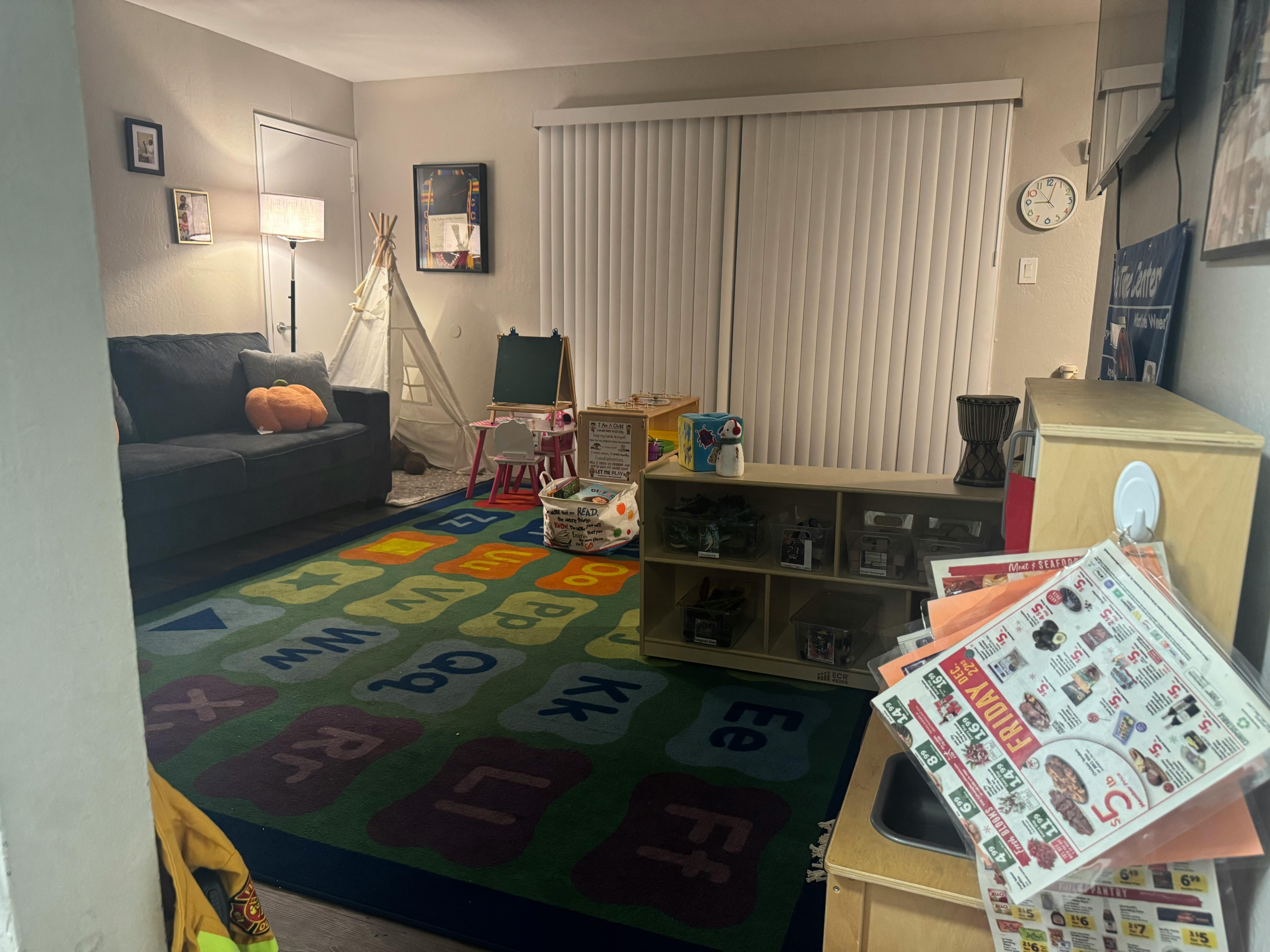 Living room with an alphabet rug, sofa, and children's play items