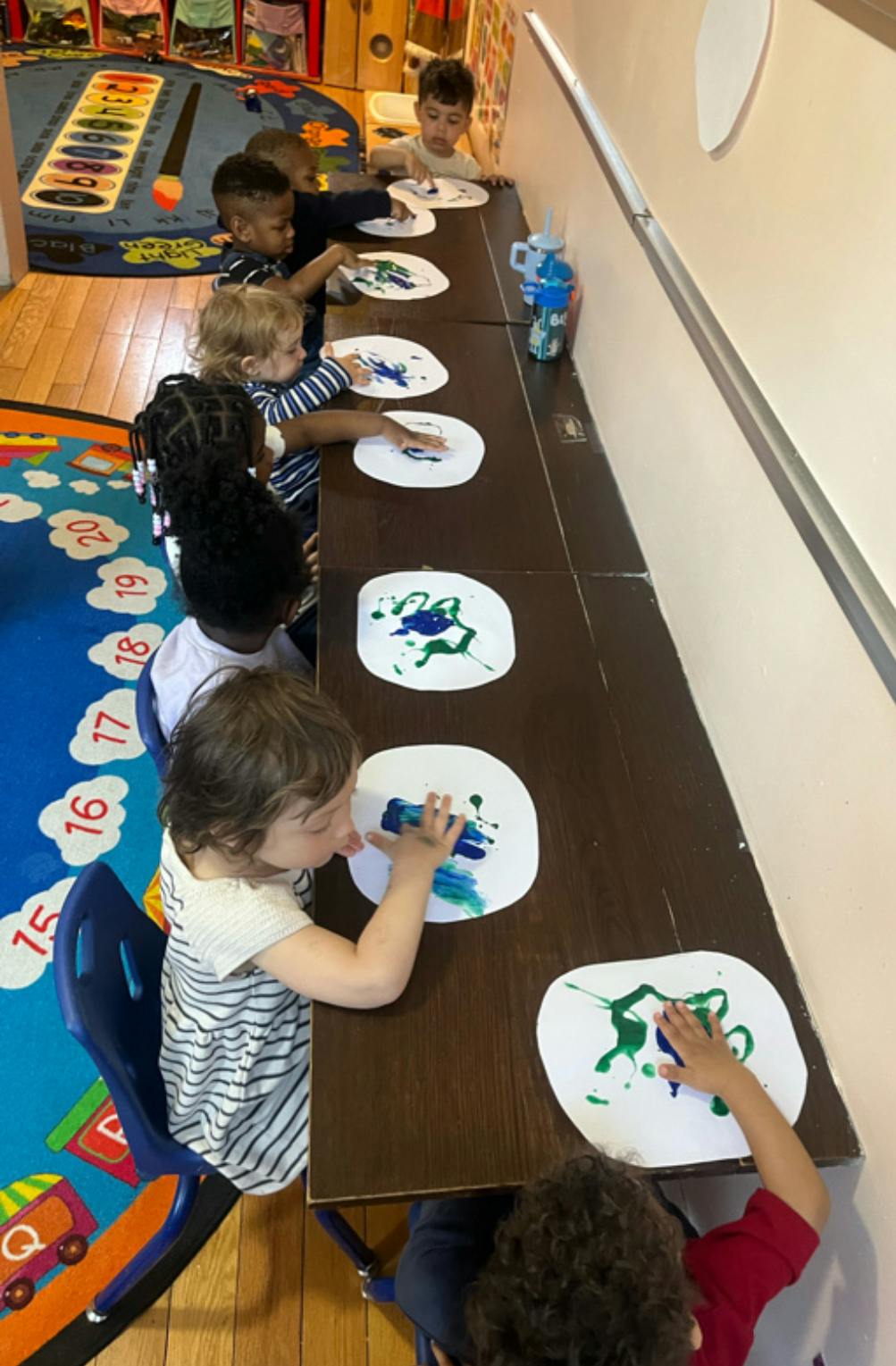 Children painting at a long table