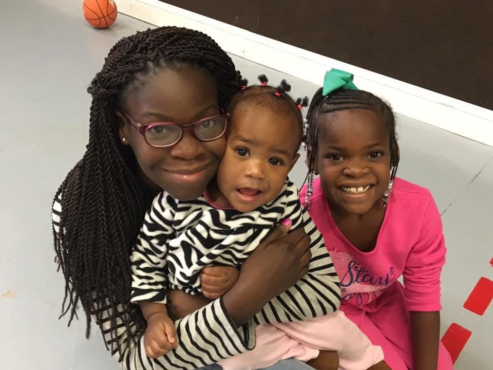Person holding a child, with another child next to them
