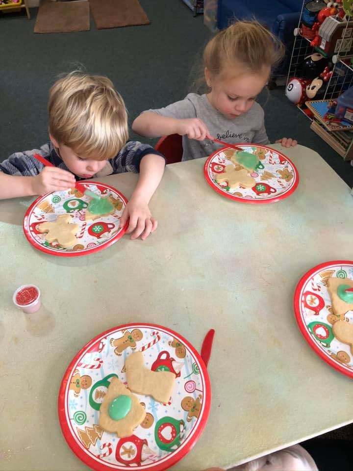 Two children decorating cookies at a table