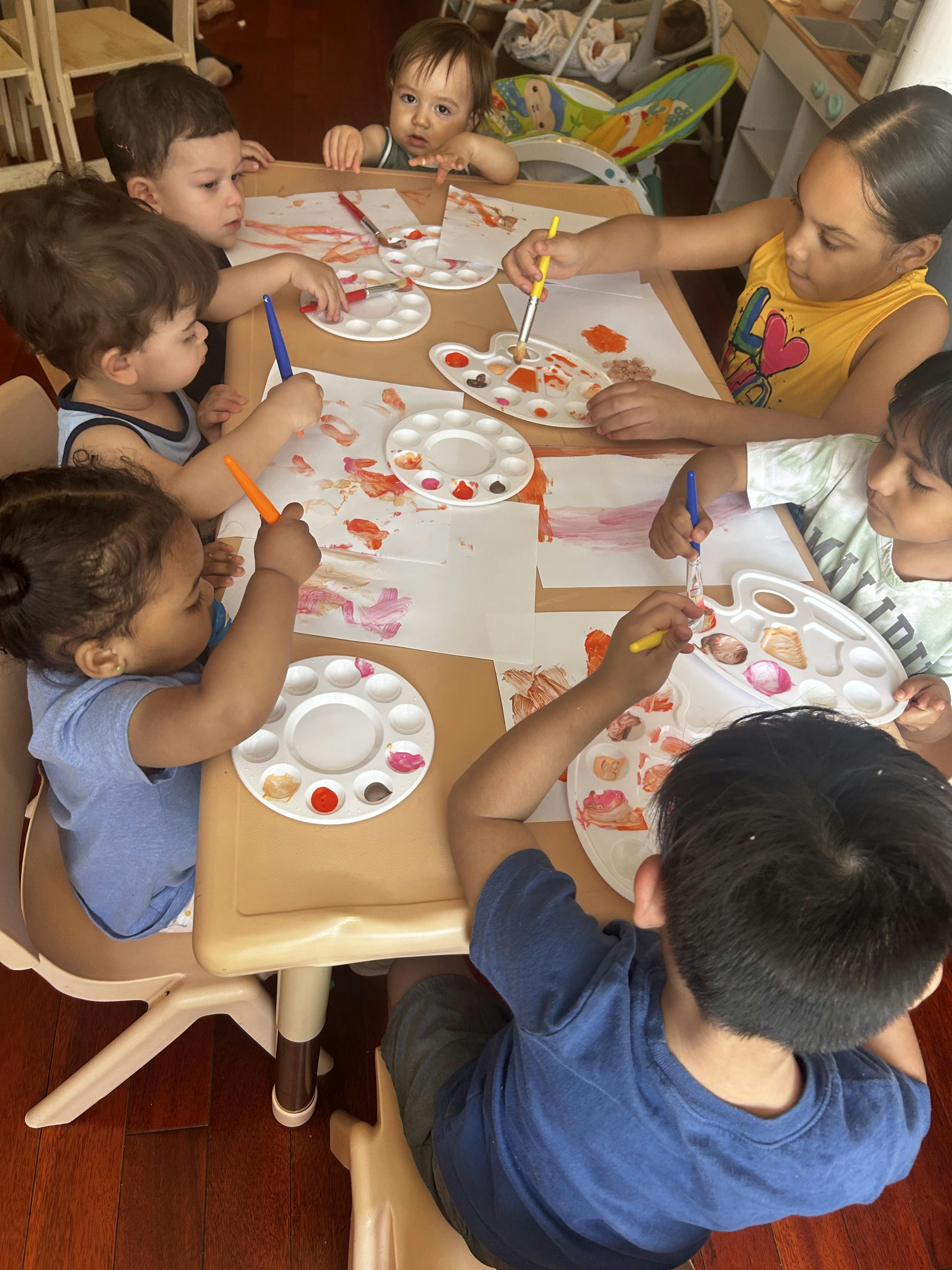Group of children painting with brushes and palettes at a table