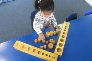 Child playing with wooden cylinder blocks on a blue table