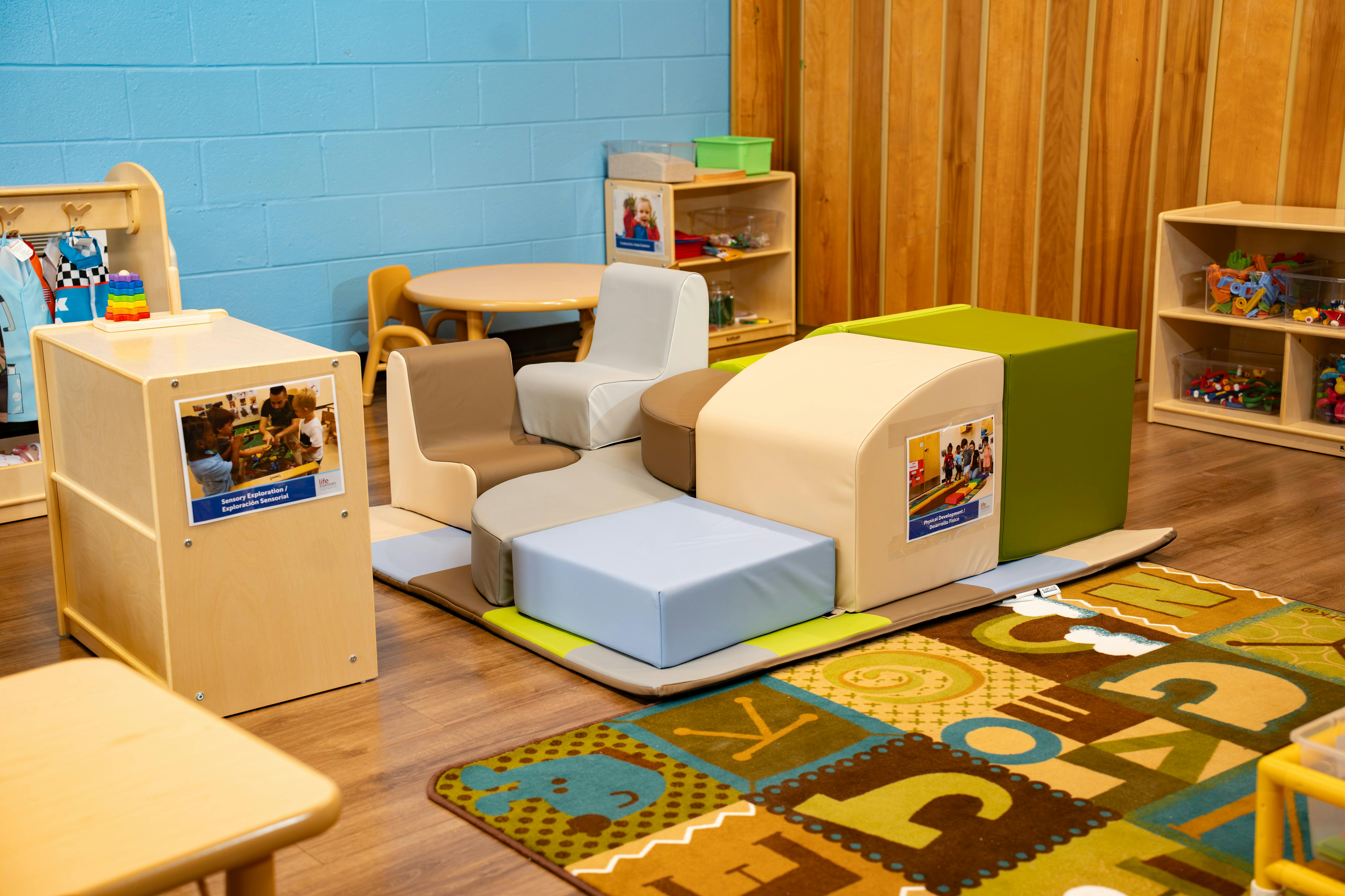 Children's play area with soft play blocks, alphabet rug, and toys