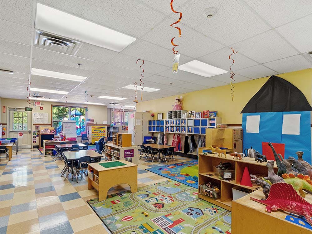 Colorful preschool classroom with tables, chairs, and play areas