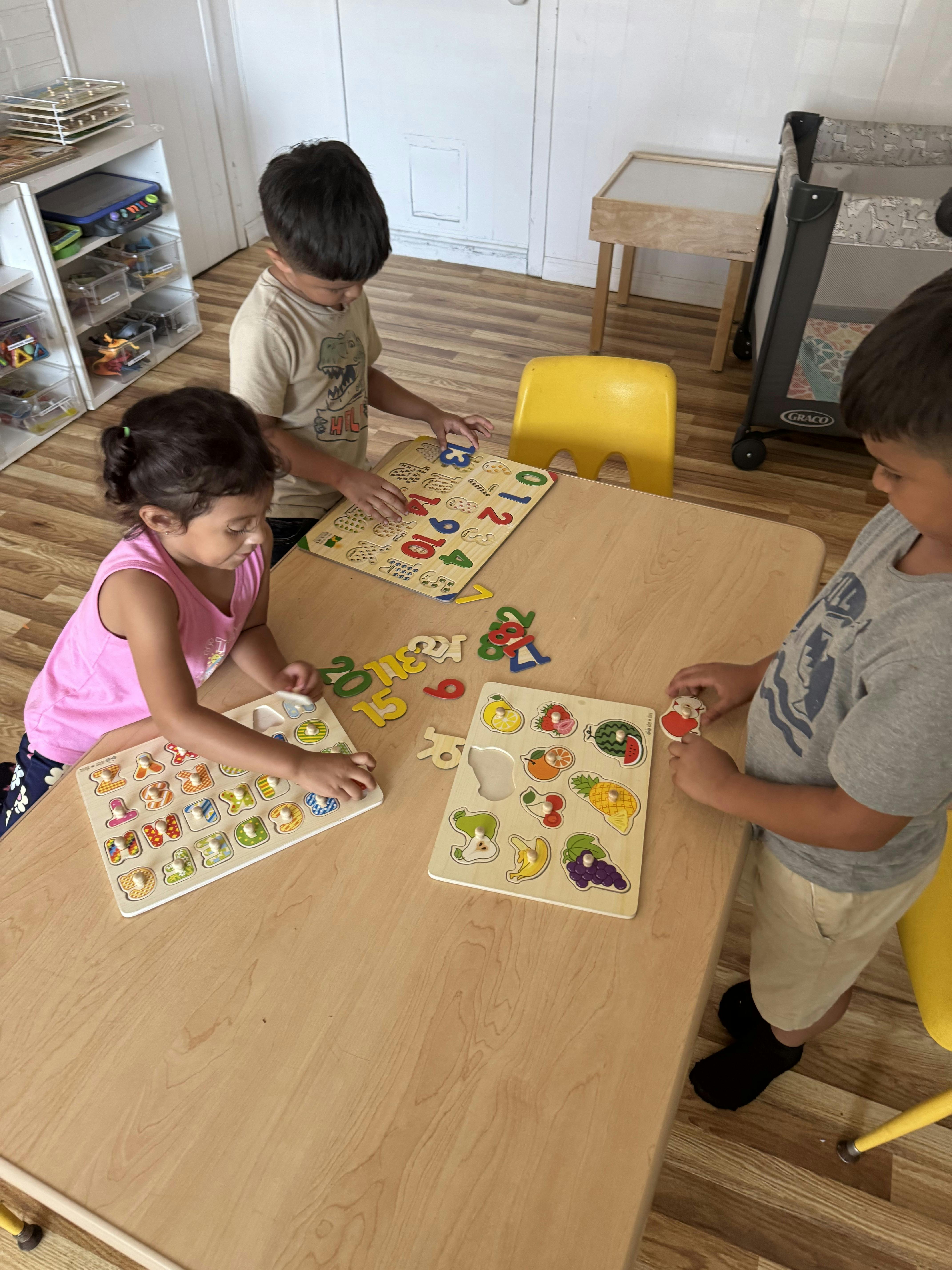 Three children playing with puzzles at a table