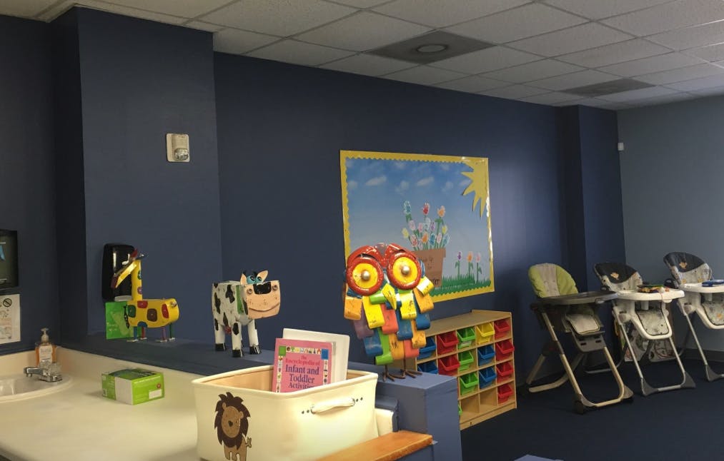 Children's room with toys, high chairs, and a colorful wall hanging