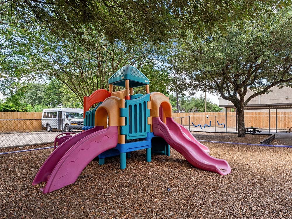 Colorful playground structure with slides on wood chip ground