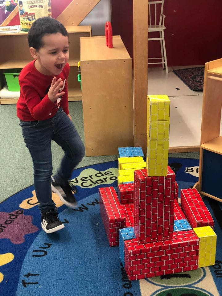 Child playing with large building blocks in a classroom