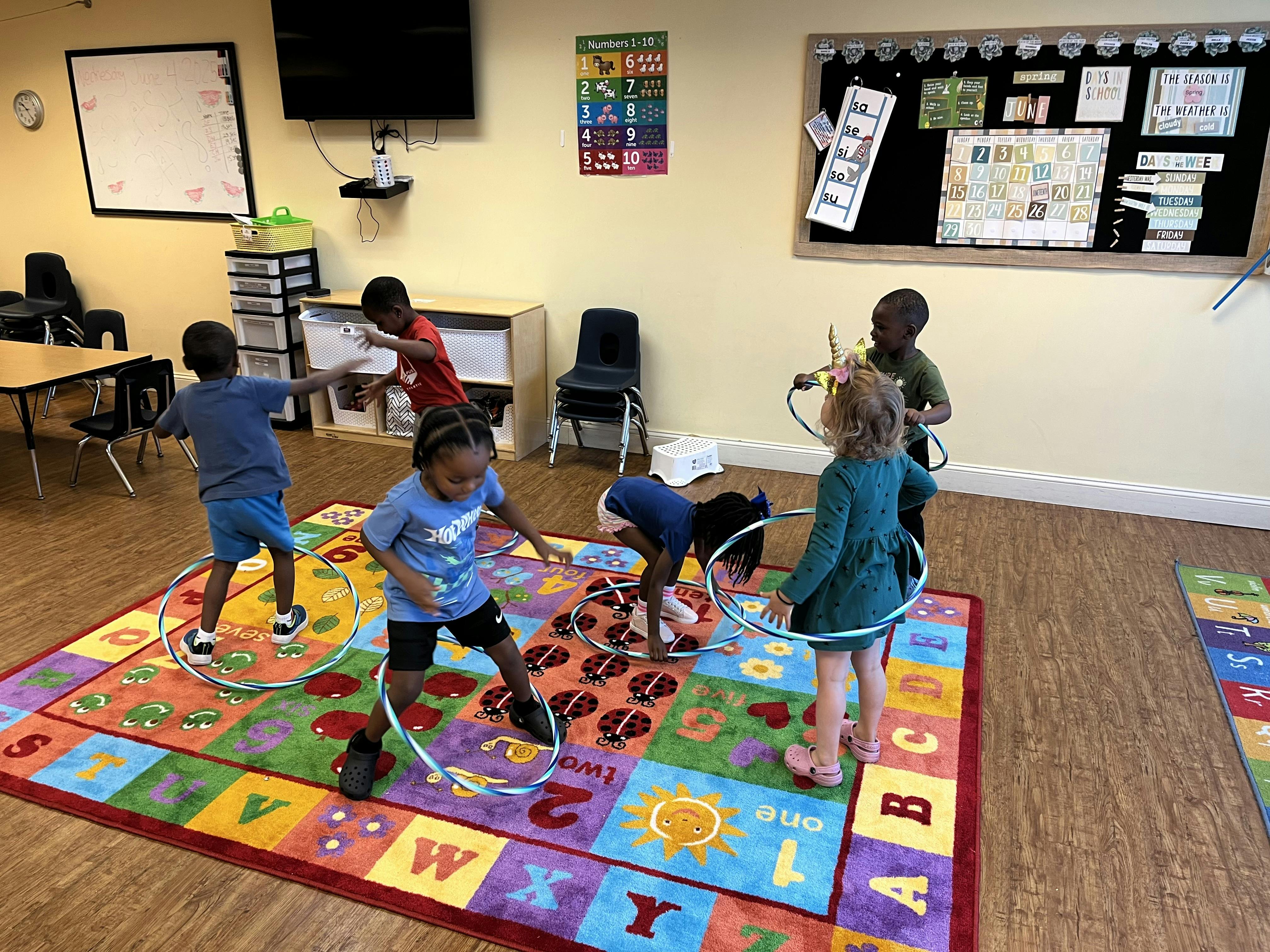 Children playing with hula hoops on a colorful alphabet rug in a classroom