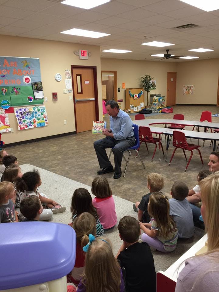 Person reading a book to a group of children in a classroom