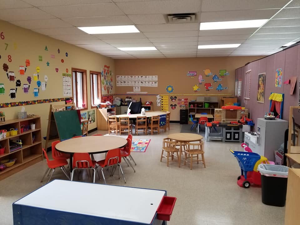 Classroom with small tables and chairs, shelves, and wall decorations