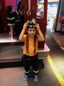 Child wearing a firefighter helmet and costume