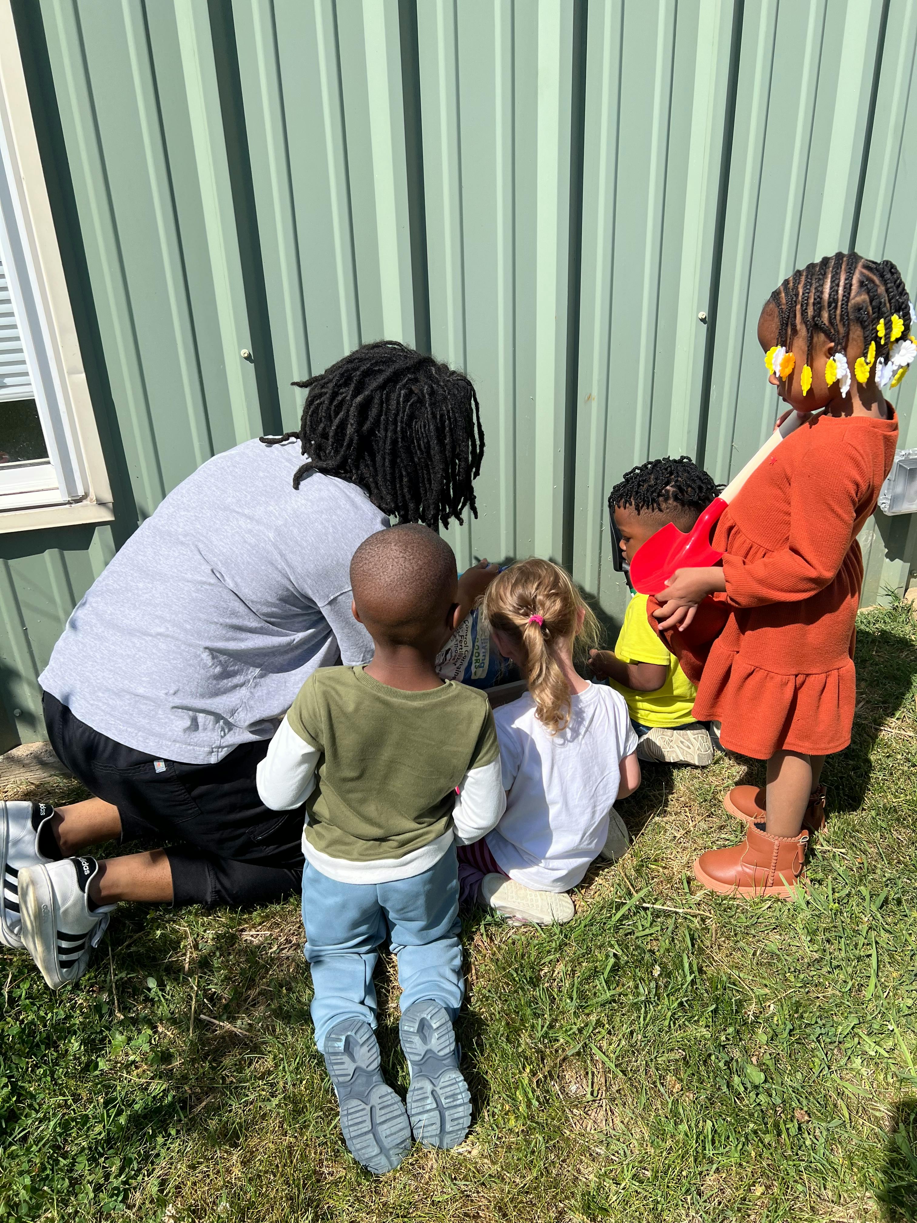 Adult and three children sitting on grass