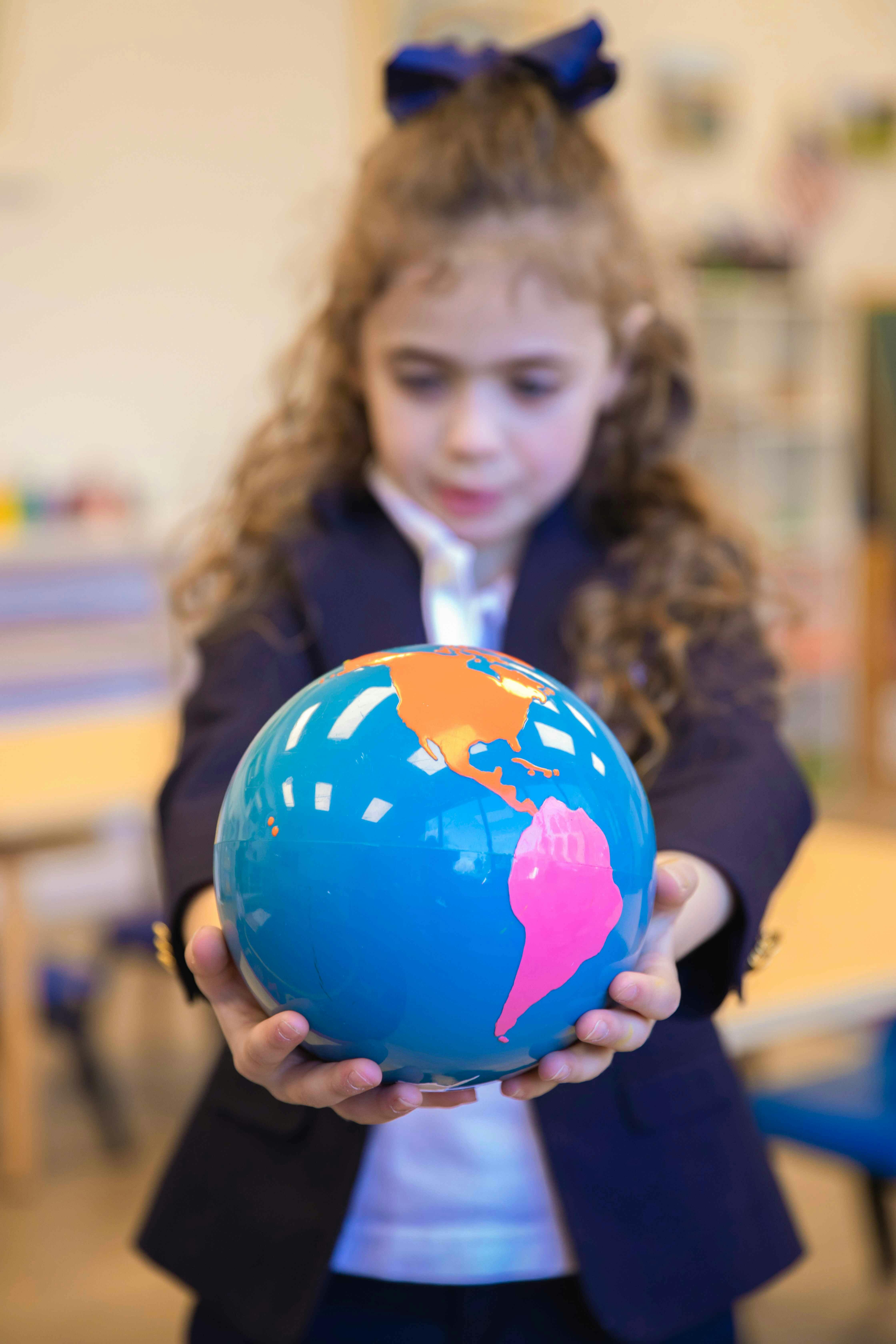 Child holding a globe in a classroom